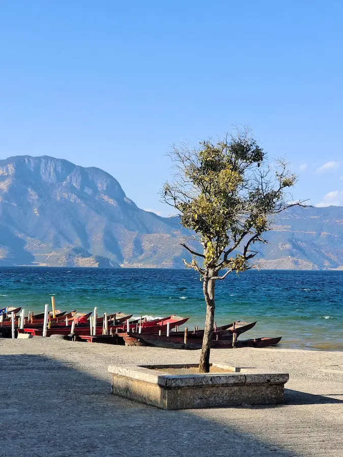 Wooden boats and distant mountains on Lugu Lake in Yunnan
