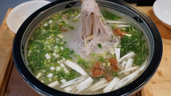 Crossing bridge rice noodle soup with sliced raw meat cooked in hot broth